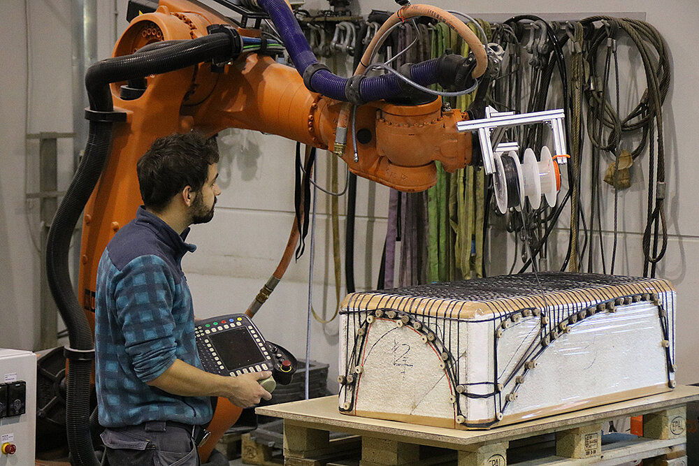 the photo shows the robot-assisted placement of mineral-impregnated carbon yarns