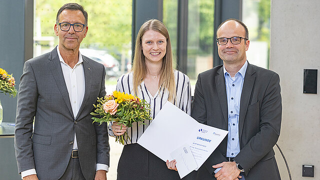 Adrian Diaconu (HOCHTIEF Infrastructure GmbH, Deutschland Südost) und der Prorektor Forschung Prof. Dr. Lars Bernard übereichen den Preis an Josiane Herfort 