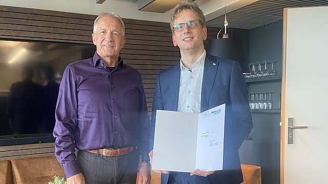 Dr. Olivier Reinertz und Dekan Professor Wolfgang Schröder. Olivier Reinertz zeigt die Ernennungsurkunde